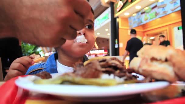 Un gamin mange au centre commercial. — Video