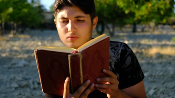 Jovem lendo Alcorão ao ar livre — Vídeo de Stock