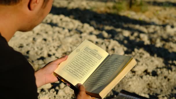 Joven leyendo Quran al aire libre — Vídeo de stock