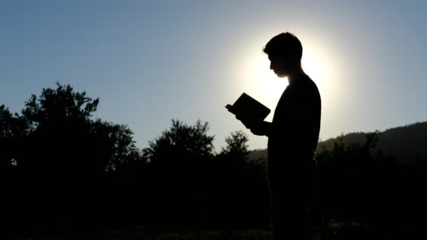 Silhouet man die de Koran leest — Stockvideo