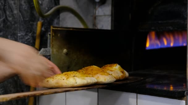 Шеф-повар достает из духовки новые хлебобулочные изделия — стоковое видео