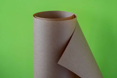 Yeşil arka planda kahverengi kağıt rulosu.