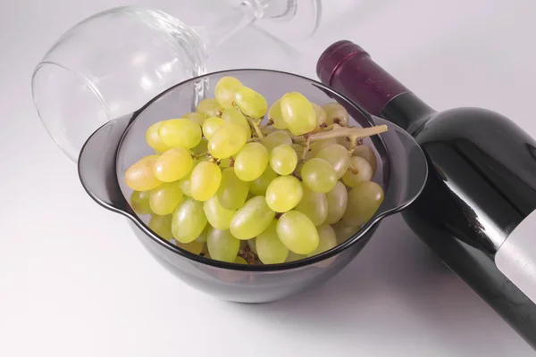 Ripe grapes, a bottle of wine and an empty glass.