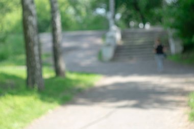 Parkta. Yeşil yaz ağaçları. İnsan figürü. Bokeh efektli bulanık resim.