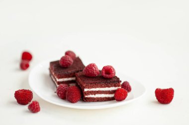 Olgun ahududu meyveleriyle süslenmiş çikolatalı ahududu bisküvisi. Beyaz beton arka planda tatlı bir çilek. Yüksek kalite fotoğraf