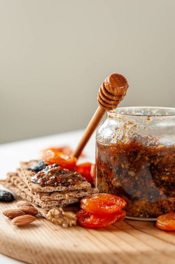 Sağlıklı vitaminli vegan tatlı. Tahta bir tahtanın üzerindeki kavanozda kurutulmuş meyve, fındık, bal ve limon karışımı. Seçici odak.