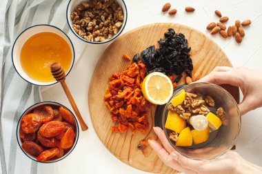 Kurutulmuş meyve, fındık ve baldan oluşan sağlıklı bir vejetaryen tatlı yapma süreci. Malzemeler beyaz bir masada. Yukarıdan bak. Evde yemek tecrübeleri.