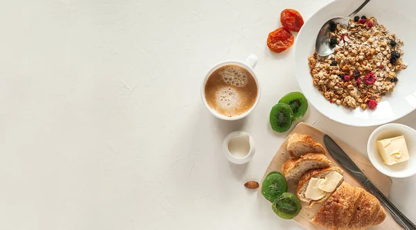 Téli reggeli croissant-nal, müzlivel és szárított gyümölccsel a világosszürke asztalon. Egészséges reggeli. — Stock Fotó