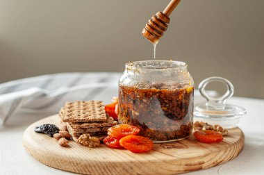 Sağlıklı vitaminli vegan tatlı. Tahta bir tahtanın üzerindeki kavanozda kurutulmuş meyve, fındık, bal ve limon karışımı. Seçici odak.