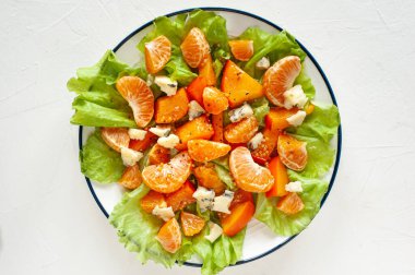 Parlak tatlı ve ekşi salata, hurma, mandalina ve mavi peynir. Kış vitaminleri. Yakın plan. Yukarıdan görüntüle.