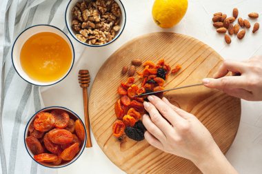 Kurutulmuş meyve, fındık ve baldan oluşan sağlıklı bir vejetaryen tatlı yapma süreci. Malzemeler beyaz bir masada. Yukarıdan bak. Evde yemek tecrübeleri.