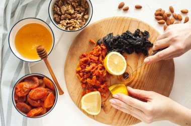Kurutulmuş meyve, fındık ve baldan oluşan sağlıklı bir vejetaryen tatlı yapma süreci. Malzemeler beyaz bir masada. Yukarıdan bak. Evde yemek tecrübeleri.