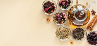 Çaydanlığın yanındaki yeşil, siyah ve bitkisel çayın farklı türleri bej arka planda sıcak demlenmiş çayla dolu. Lezzetli organik içecekler. Yukarıdan bak. Metin Paneli için bir yer