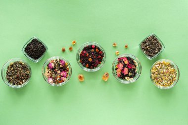 Yeşil arka planda farklı türde yeşil, siyah ve bitkisel çay. Lezzetli organik içecekler. Yukarıdan bak. Metin için bir yer.