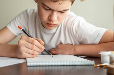 Genç bir çocuk resim çizer. Elinde kalem olan bir gencin eli. Yaratıcı hobi. Resim dersi. Yakın çekim ve seçici odaklanma.