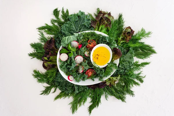 Ensalada de col rizada, hierbas, tomates y rábanos en un plato ovalado blanco con ingredientes alrededor sobre un fondo blanco. Comida vegana. Alimentación saludable. Almuerzo dietético. —  Fotos de Stock