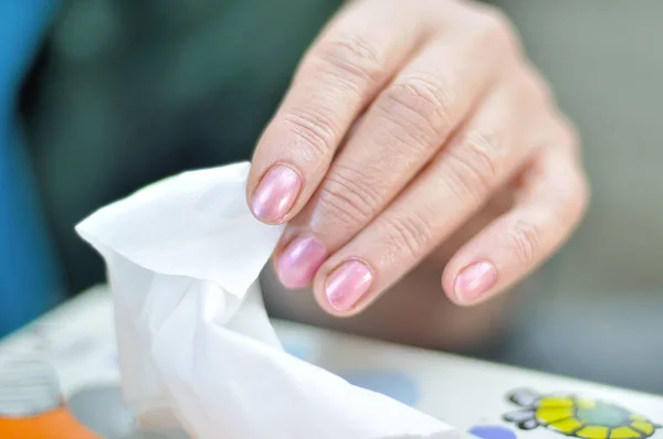 the female hand pulls a white tissue (napkin) from a box for cleaning