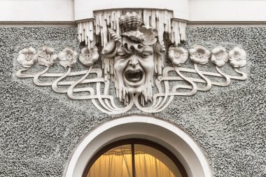 Stylized head among the flowers in bas-relief in Riga clipart