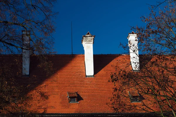 红瓦屋顶与烟囱上蓝蓝的天空背景 — 图库照片