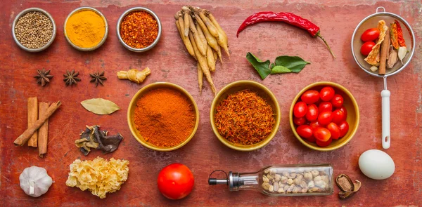Mixed spices and herbs on red background.