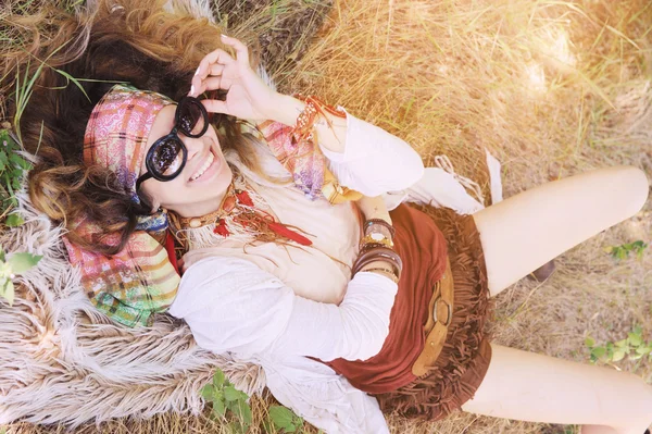 Boho style happy smiling girl portrait lying on a hay and fur — Stock Photo, Image