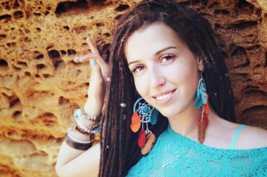 Dreadlocks saç modeli, giyen genç gülümseyen kadın portresi giymiş mavi dantel elbise ve mavi boho chic küpe