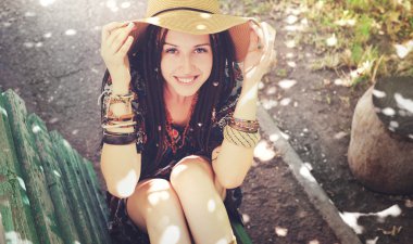 Pretty smiling young girl with dreadlocks dressed in boho style, resting outdoor clipart