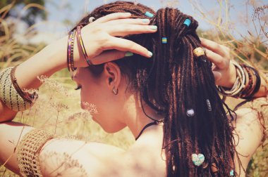 Dreadlocks saç modeli giymiş güzel genç kadın bir at kuyruğu toplandı ve çeşitli boncuklar dekore edilmiş