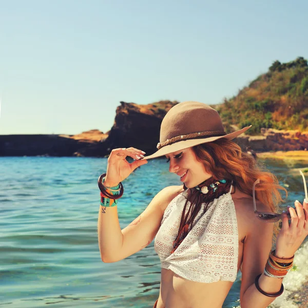 Boho elegáns karkötők és a kalap öltözött nő utazó közelében a tenger partjától, mosolygott, és gyönyörű, túrázás, — Stock Fotó