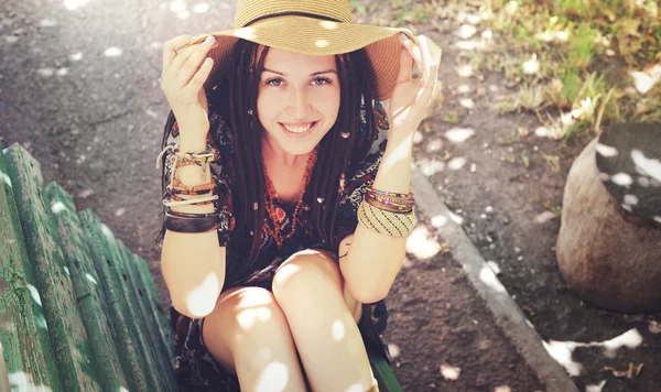 Chica joven bastante sonriente con rastas vestidas en estilo boho, descansando al aire libre — Foto de Stock