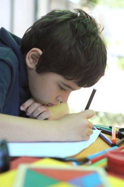 Çocuk ödevini arka bahçede, dışarıda yapıyor.