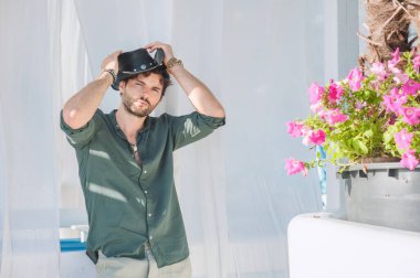 Siyah şapkalı, yeşil gömlekli, açık hava fotoğraflı seksi bir adam.