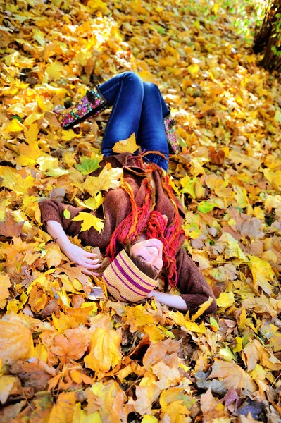 Woman resting on autumn leaves in park. — Stock Photo, Image