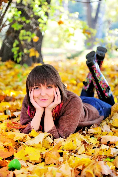 Woman lying on her stomach on autumn leaves. — Stock Photo, Image