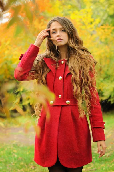 Mujer de moda joven vestida con abrigo rojo en el parque de otoño . —  Fotos de Stock