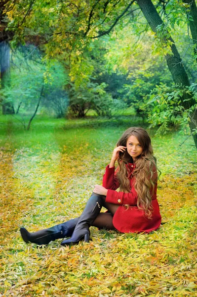 Woman in red sitting in autumn park. — Stock Photo, Image