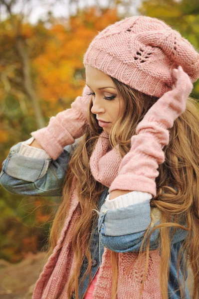 Woman dressed in pink knitted hat, scarf and gloves in autumn park. — Stock Photo, Image