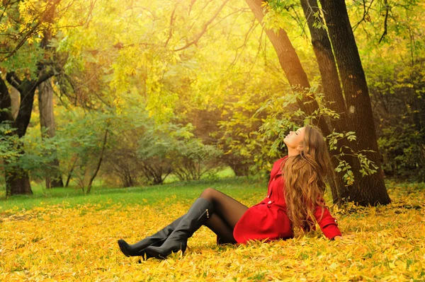 Vrouw gekleed in rode jas ontspannen in herfst park. — Stockfoto