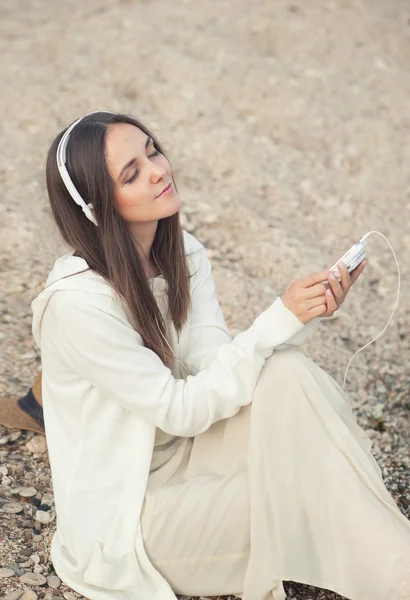 Bella donna rilassarsi ascoltando musica con il telefono contro la sabbia del mare . — Foto Stock