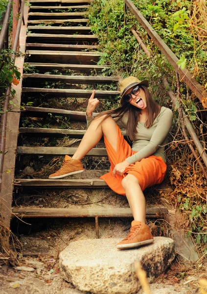 Engraçado menina mostrar língua se divertir na velha escada de madeira . — Fotografia de Stock