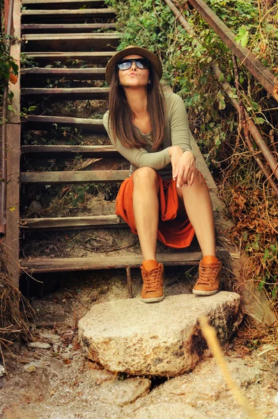 Muchacha divertida de la moda joven sentado en las viejas escaleras de madera . — Foto de Stock