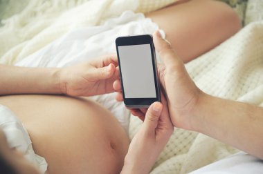 Belly ve gelecekteki baba smartphone tutan elleri ile hamile kadının el.
