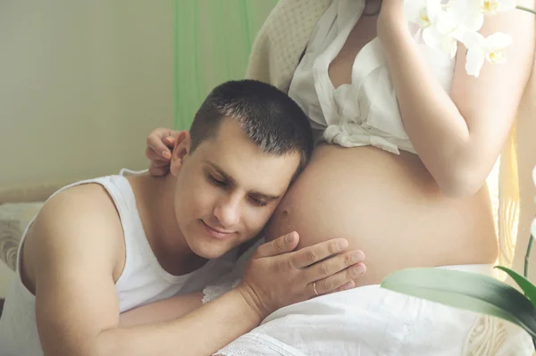 Happy smiling future dad give a hug to the belly of his pregnant wife. — Stock Photo, Image