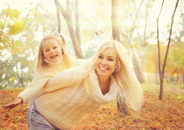 Happy cheerful mother holding smiling baby girl and play  together in sunny autumn park. — Stok fotoğraf