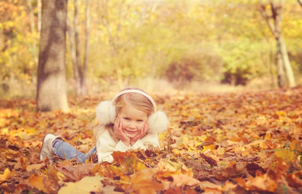 Pequena menina loira retrato deitado no outono amarelo bordo folhas estendidas mãos e sorrindo . — Fotografia de Stock