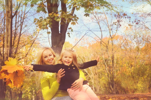 Beautiful young mother and little daughter playing together in park. — Stok fotoğraf