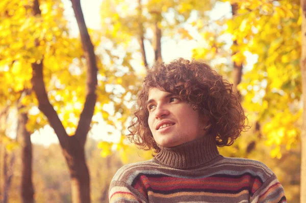 Portrait of smiling attractive man dressed in striped sweater, oudoor in autumn park. — ストック写真