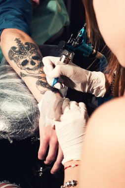 Bir yandan, tacı olan siyah kafatası bir dövme yapma işlemi gösteren kapatın