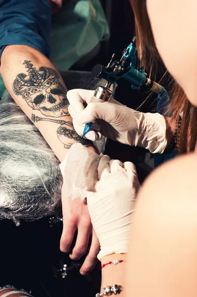 Close-up waarin proces van het maken van een tatoeage op een hand, zwarte schedel met kroon — Stockfoto