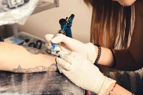 Close-up van handen waarin proces van het maken van tatoeage op een hand door meester. — Stockfoto